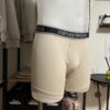 Photo prise de côté du boxer beige armani avec la bande couleur marine où le logo est inscrit