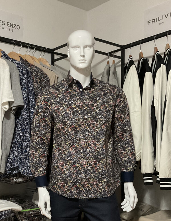 Photo prise de devant de la chemise STRETCH premium à motifs PUZZLE avec des nuances de différentes couleurs, avec les manches retournés d’un autre ton de couleur, ce qui donne un aspect plus chic à la chemise. On relève la couleur bleu marine