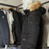 Photo prise de cote du blouson couleur noir avec fourrure amovible de Frilivin. On peut voir quelques boutons dorés.