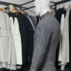 Photo prise de côté du pull torsadé au toucher cachemire gris de la marque Top Monday. On voit qu’il est associé avec le pantalon stretch beige sable de la marque Yves Enzo.