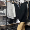 Photo prise de côté (photo complète) du pull torsadé au toucher cachemire noir de la marque Top Monday. On voit qu’il est associé avec le pantalon stretch beige sable de la marque Yves Enzo.