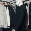 Photo prise de côté du pull torsadé au toucher cachemire noir de la marque Top Monday. On voit qu’il est associé avec le pantalon stretch beige sable de la marque Yves Enzo.