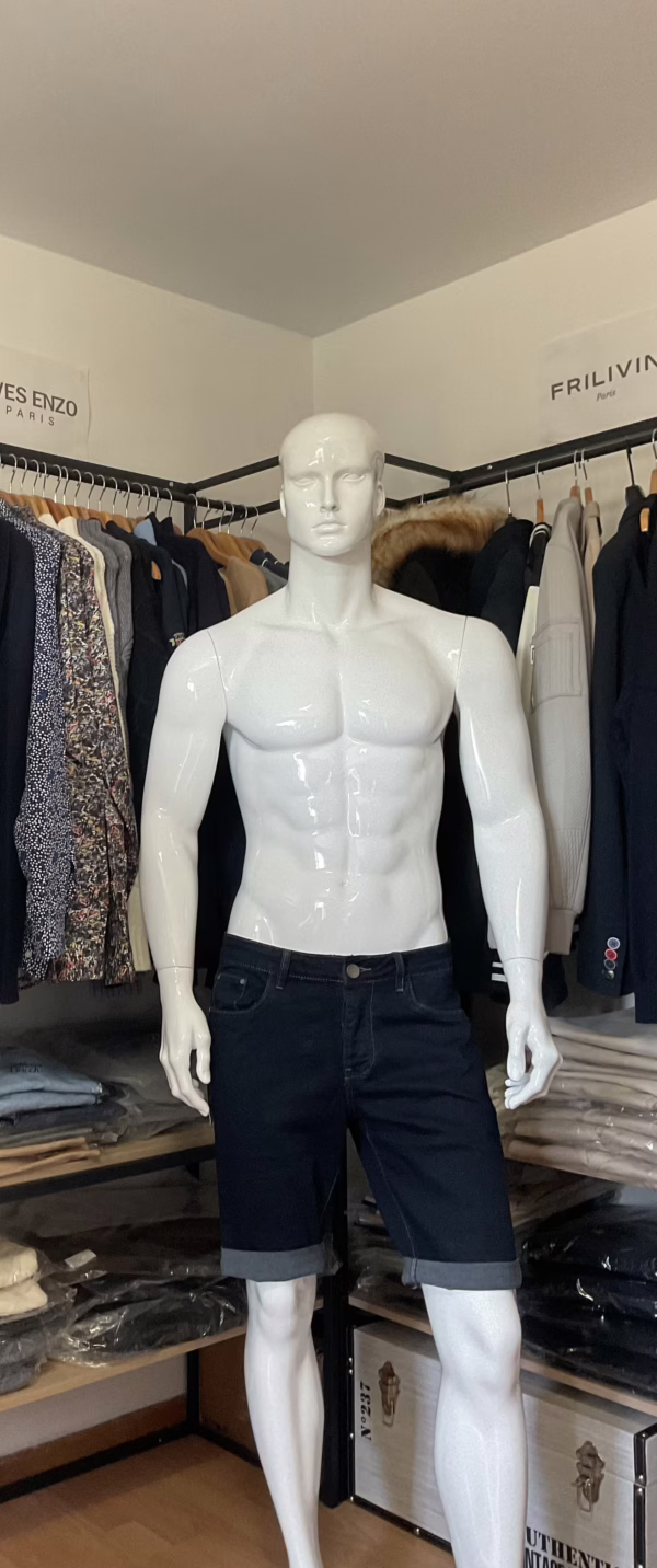 La photo de face présente le short en jean bleu brut de la marque Omnimen, une pièce à l’esprit casual et urbain. Les revers visibles au bas du short lui donnent un style décontracté maîtrisé. La fermeture se fait par un bouton en métal apparent, ajoutant une touche robuste au design. Côté pratique, le short dispose de trois poches sur le devant : une à droite, une à gauche, et une petite poche additionnelle sur la gauche, subtile mais fonctionnelle. Un basique revisité, parfait pour affirmer un style estival sans faire de compromis sur le confort.