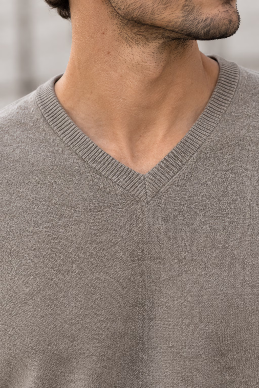 Gros plan détaillé du col V et de la texture douce et luxueuse du pull en cachemire taupe "five ever". Le grain de la maille est clairement visible.