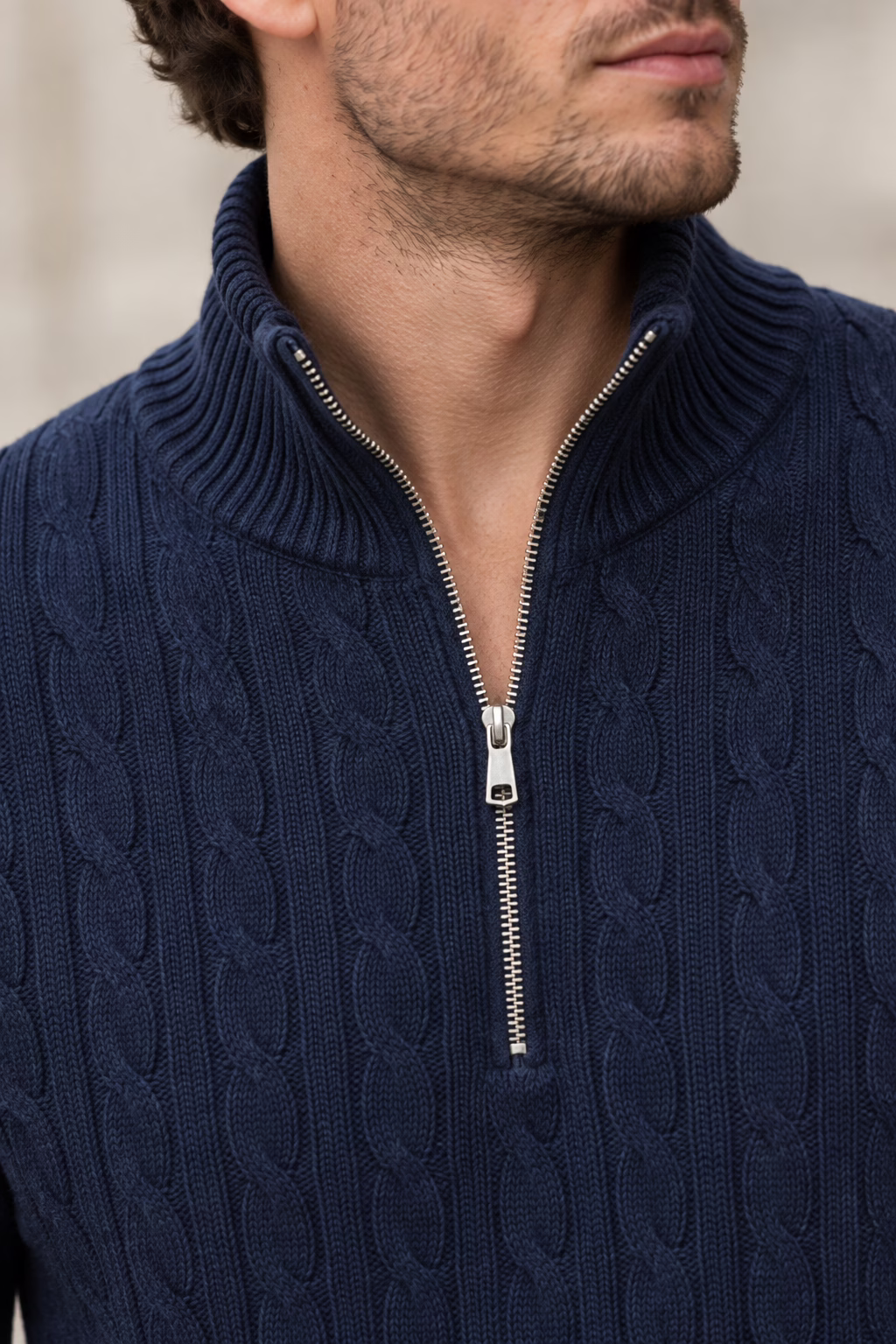 Gros plan sur le col zippé en métal argenté et le motif de maille torsadée détaillée du pull bleu marine Five Ever pour homme.